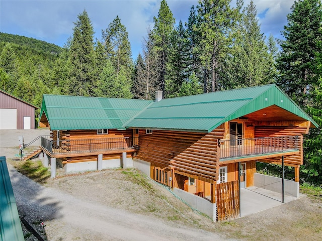 104 Swede Gulch Rd, Libby, MT 59923 - log cabin featuring log siding, metal roof, a wooded view, and a chimney