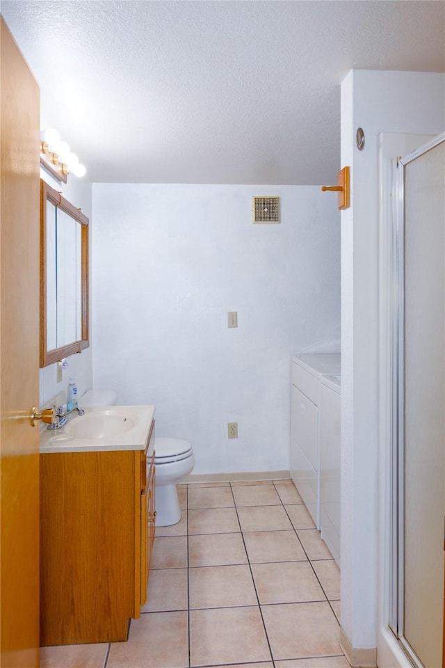 104 Swede Gulch Rd, Libby, MT 59923 - bathroom featuring washing machine and dryer, vanity, a shower stall, a textured ceiling, and toilet