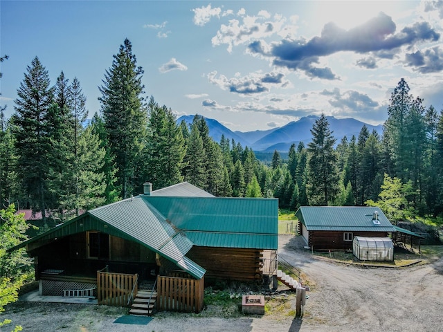 104 Swede Gulch Rd, Libby, MT 59923 - view of front facade featuring a mountain view, a view of trees, metal roof, and a chimney
