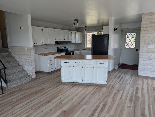 11 City Shop Rd, Shelby, MT 59474 - kitchen featuring freestanding refrigerator, black range, a sink, white cabinetry, and under cabinet range hood
