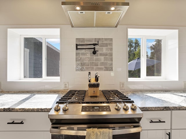 871 Conrad Dr, Kalispell, MT 59901 - kitchen featuring stainless steel gas range oven, light stone countertops, white cabinets, range hood, and tasteful backsplash