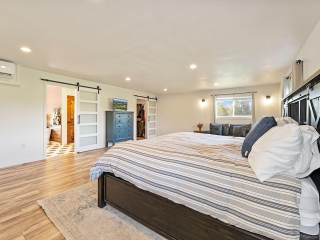 871 Conrad Dr, Kalispell, MT 59901 - bedroom featuring a barn door, light wood-style floors, a walk in closet, a wall unit AC, and recessed lighting