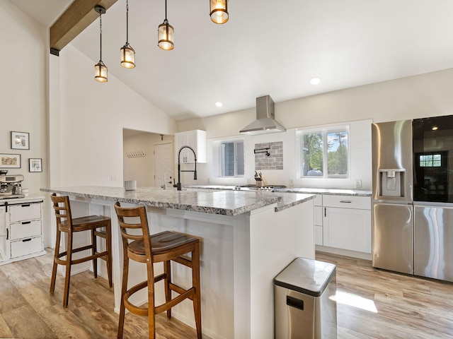 871 Conrad Dr, Kalispell, MT 59901 - kitchen featuring wall chimney exhaust hood, stainless steel fridge, light wood-style flooring, lofted ceiling, and white cabinets