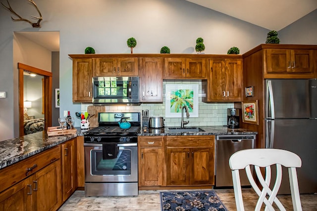 2475 E Lakeshore Dr, Whitefish, MT 59937 - kitchen featuring appliances with stainless steel finishes, a sink, backsplash, dark stone counters, and high vaulted ceiling