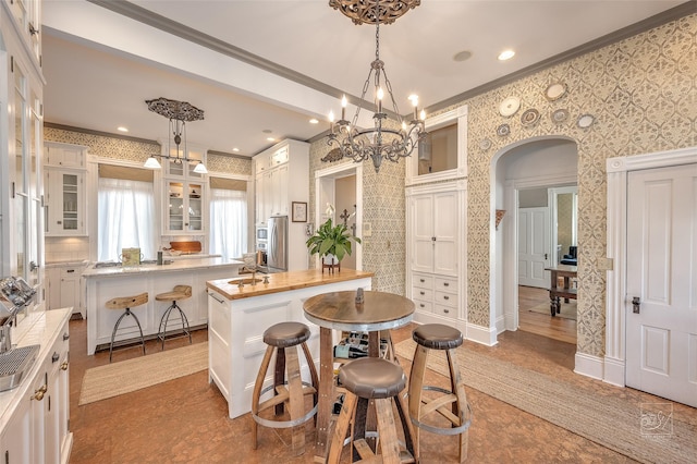 902 N Park Ave, Helena, MT 59601 - kitchen with a chandelier, a kitchen island, ornamental molding, arched walkways, and white cabinets