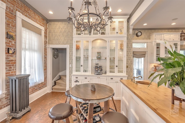902 N Park Ave, Helena, MT 59601 - dining room with ornamental molding, baseboards, a chandelier, brick wall, and wallpapered walls