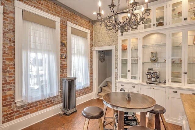 902 N Park Ave, Helena, MT 59601 - dining room with baseboards, crown molding, a chandelier, and brick wall