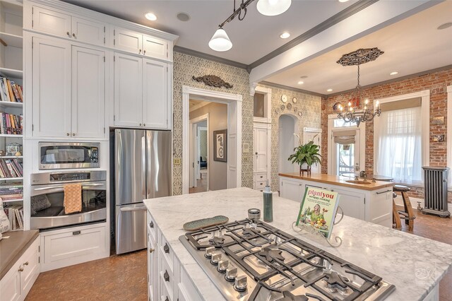 902 N Park Ave, Helena, MT 59601 - kitchen with stainless steel appliances, crown molding, a chandelier, white cabinetry, and decorative light fixtures