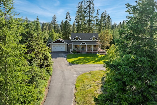 13471 Sundance Trl, Bigfork, MT 59911 - view of front of property with covered porch, driveway, a front yard, a garage, and a forest view