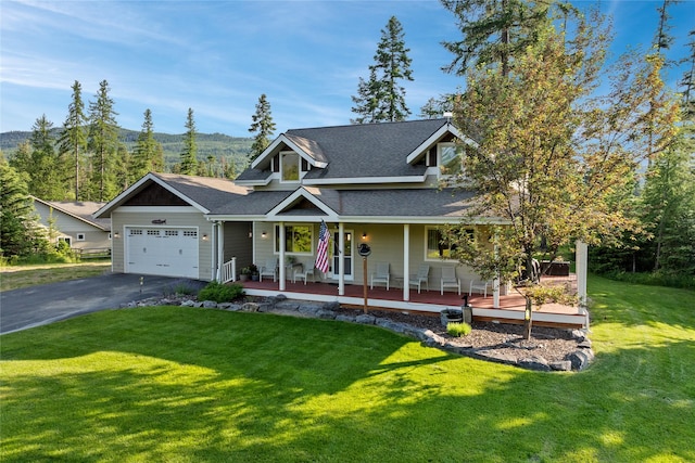 13471 Sundance Trl, Bigfork, MT 59911 - view of front of property featuring a garage, driveway, a shingled roof, a front yard, and a porch