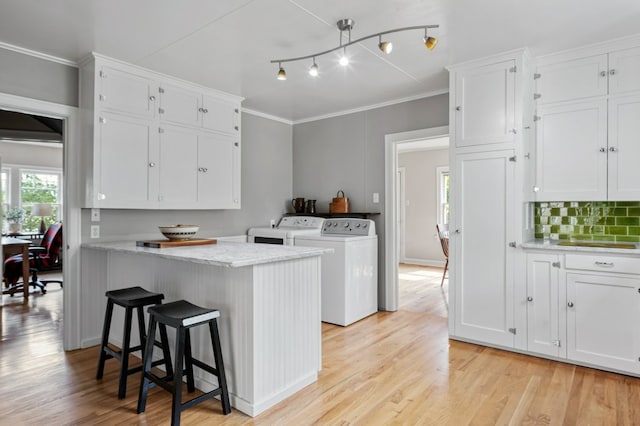 2606 View Dr, Missoula, MT 59804 - kitchen with separate washer and dryer, white cabinetry, a breakfast bar, light wood finished floors, and light stone countertops