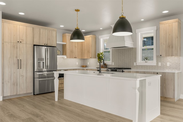 7018 Max Dr, Missoula, MT 59803 - kitchen featuring stainless steel fridge with ice dispenser, light brown cabinets, premium range hood, light countertops, and a kitchen island with sink