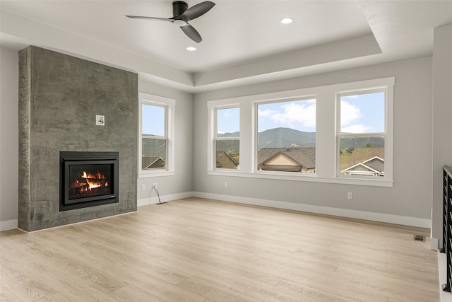 7018 Max Dr, Missoula, MT 59803 - unfurnished living room with a tray ceiling, a tile fireplace, wood finished floors, a ceiling fan, and baseboards