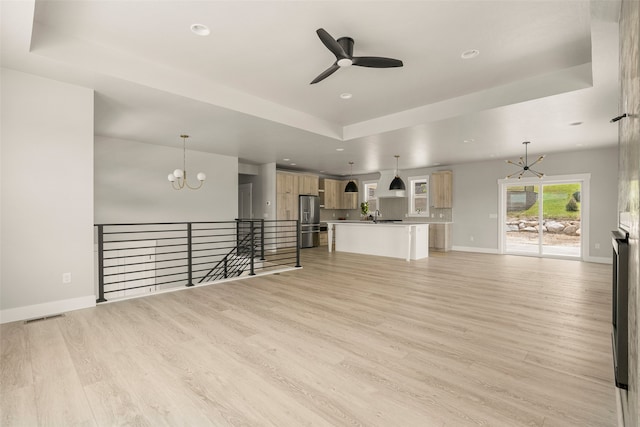 7018 Max Dr, Missoula, MT 59803 - unfurnished living room with a tray ceiling, a chandelier, a ceiling fan, light wood-style floors, and recessed lighting
