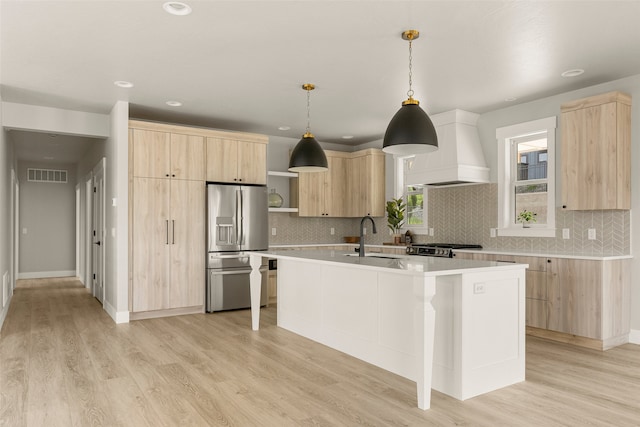 7018 Max Dr, Missoula, MT 59803 - kitchen featuring light brown cabinets, custom range hood, stainless steel refrigerator with ice dispenser, light countertops, and a sink