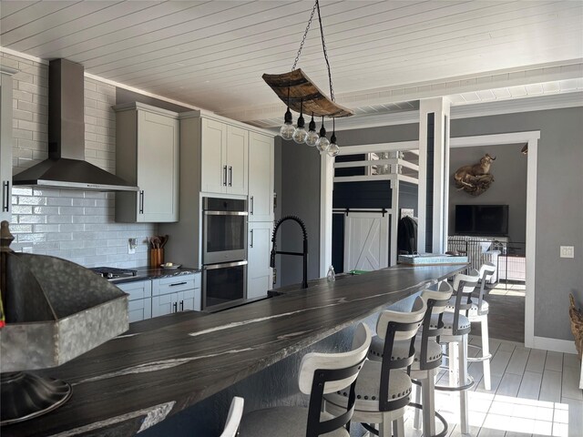 411 10th Ave NE, Choteau, MT 59422 - kitchen featuring wall chimney exhaust hood, dark countertops, double oven, tasteful backsplash, and a kitchen breakfast bar