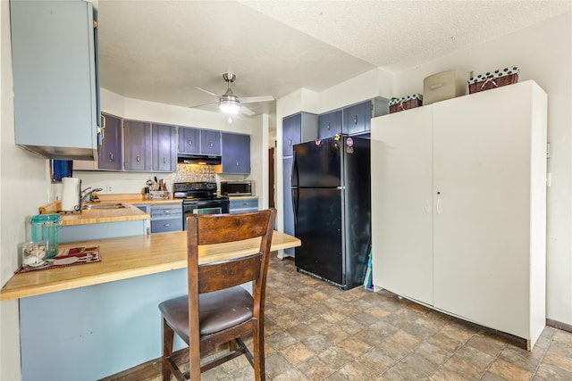 5900 Longview Dr, Missoula, MT 59803 - kitchen with black appliances, under cabinet range hood, stone finish flooring, blue cabinetry, and a sink