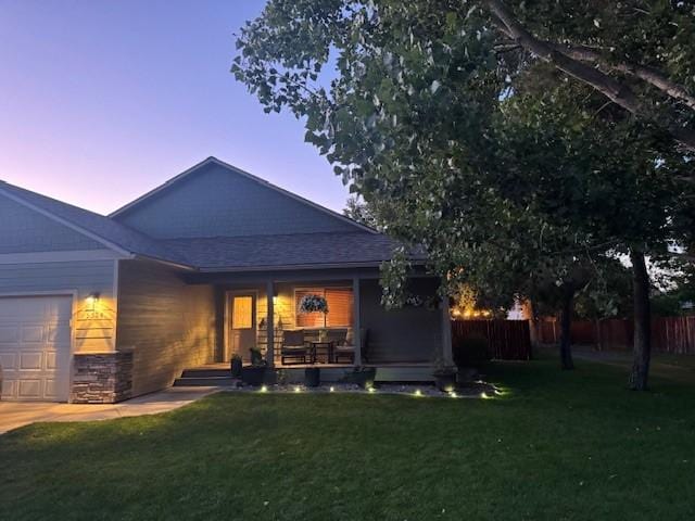 5334 Woodrow Ln, Lolo, MT 59847 - back of house at dusk with an attached garage, a porch, and roof with shingles