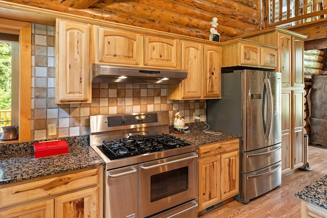 421 Swanson Lodge Rd, Troy, MT 59935 - kitchen featuring appliances with stainless steel finishes, under cabinet range hood, light wood-type flooring, backsplash, and dark stone counters