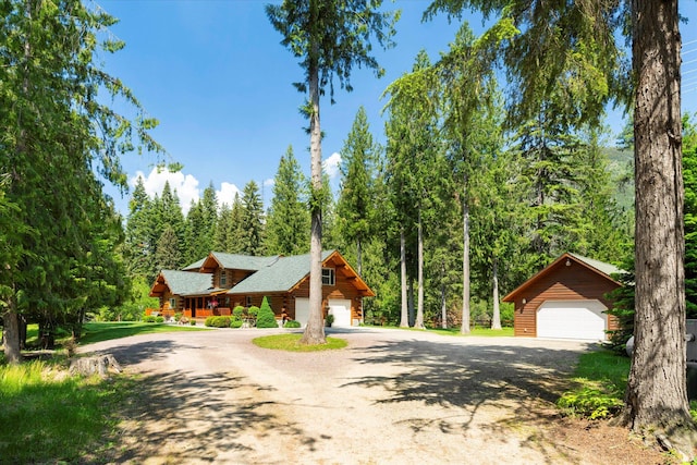 421 Swanson Lodge Rd, Troy, MT 59935 - log-style house with log siding, a detached garage, a wooded view, and dirt driveway