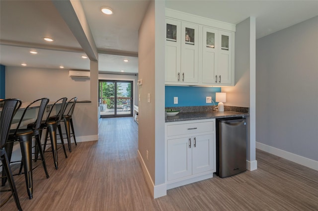 1520 Highland St, Helena, MT 59601 - kitchen featuring dark countertops, wood finished floors, baseboards, white cabinets, and a wall mounted air conditioner