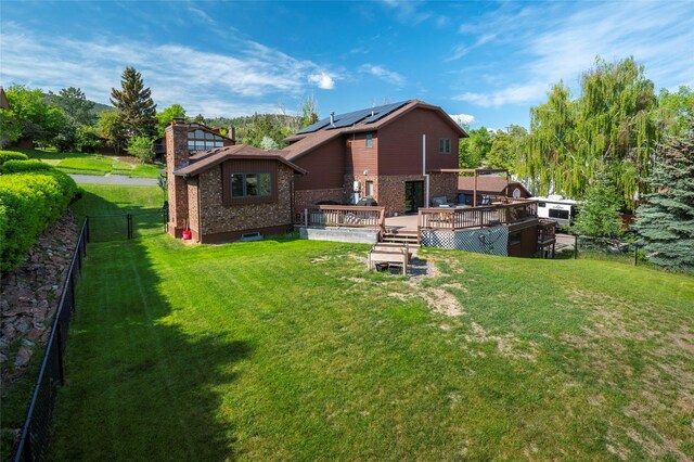 1520 Highland St, Helena, MT 59601 - rear view of house featuring a deck, brick siding, a chimney, and roof mounted solar panels