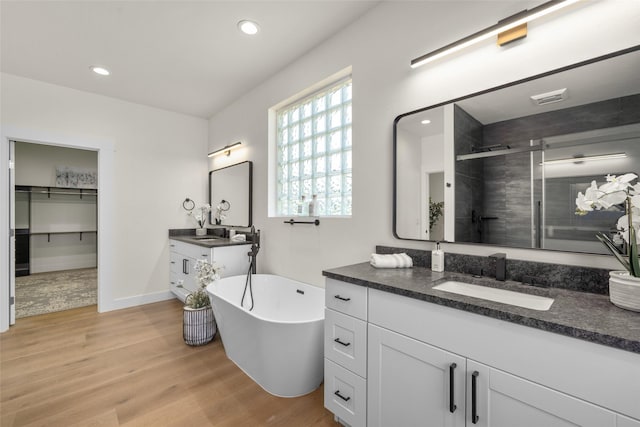 208 Cowboy Dr, Columbia Falls, MT 59912 - full bath with a stall shower, wood finished floors, two vanities, a soaking tub, and recessed lighting