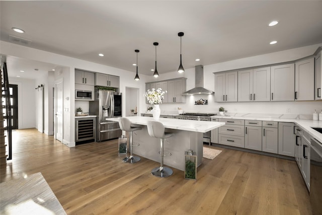 208 Cowboy Dr, Columbia Falls, MT 59912 - kitchen with wall chimney exhaust hood, gray cabinetry, stainless steel appliances, a center island, and a kitchen bar