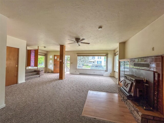 412 1st Ave E, Eureka, MT 59917 - carpeted living area featuring a wood stove, a textured ceiling, a ceiling fan, and baseboards