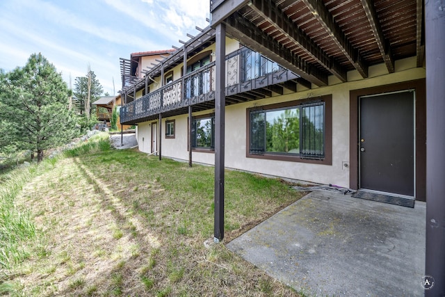 1644 Gold Rush Ave, Helena, MT 59601 - view of exterior entry featuring stucco siding, a lawn, a patio, and a wooden deck