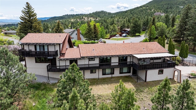 1644 Gold Rush Ave, Helena, MT 59601 - back of property with a view of trees, a mountain view, a tile roof, a balcony, and stucco siding