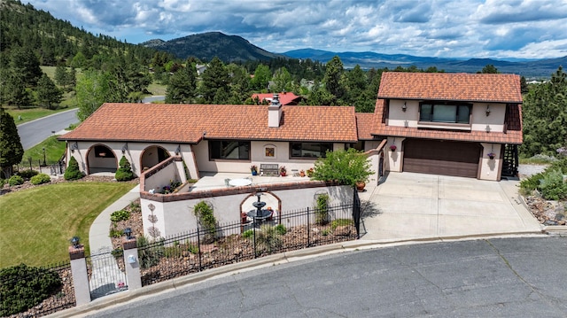 1644 Gold Rush Ave, Helena, MT 59601 - view of front of house with a tiled roof, a mountain view, concrete driveway, an attached garage, and stucco siding