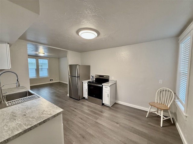506 1st Ave E Unit A, B, C, Eureka, MT 59917 - kitchen with stainless steel appliances, a sink, wood finished floors, white cabinets, and baseboards