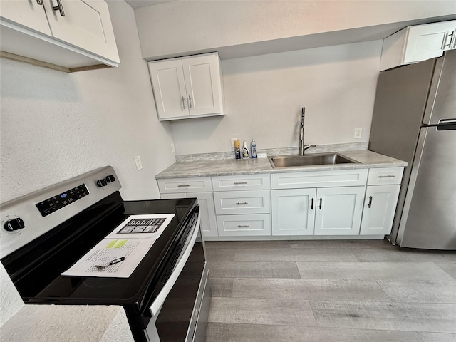 506 1st Ave E Unit A, B, C, Eureka, MT 59917 - kitchen featuring appliances with stainless steel finishes, a sink, white cabinetry, light wood-type flooring, and light countertops
