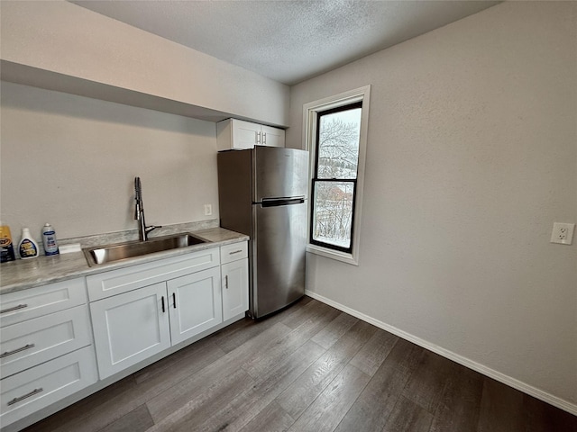 506 1st Ave E Unit A, B, C, Eureka, MT 59917 - kitchen with freestanding refrigerator, a sink, dark wood-style flooring, white cabinets, and baseboards