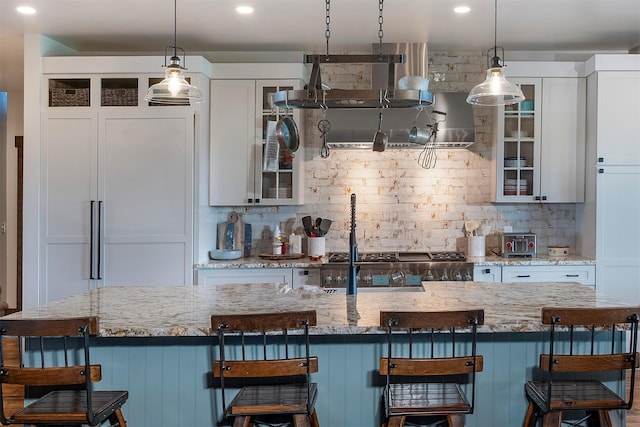 45331 Turnquist Rd, Ronan, MT 59864 - kitchen with decorative backsplash, hanging light fixtures, a breakfast bar, glass insert cabinets, and recessed lighting