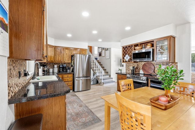 3301 Albany Ave, Butte, MT 59701 - kitchen featuring appliances with stainless steel finishes, dark countertops, tasteful backsplash, brown cabinetry, and light wood finished floors