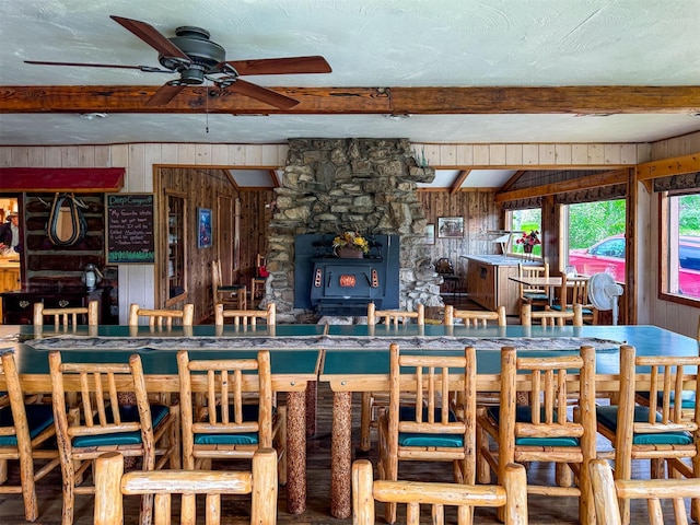2055 Teton Canyon Rd, Choteau, MT 59422 - dining area with wood walls, a ceiling fan, beamed ceiling, and a wood stove