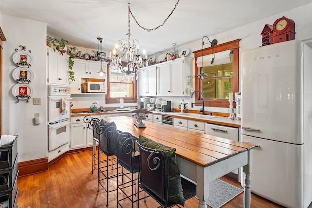 101 Lewis Ln, Hamilton, MT 59840 - kitchen with white appliances, white cabinetry, butcher block countertops, a chandelier, and light wood-style flooring