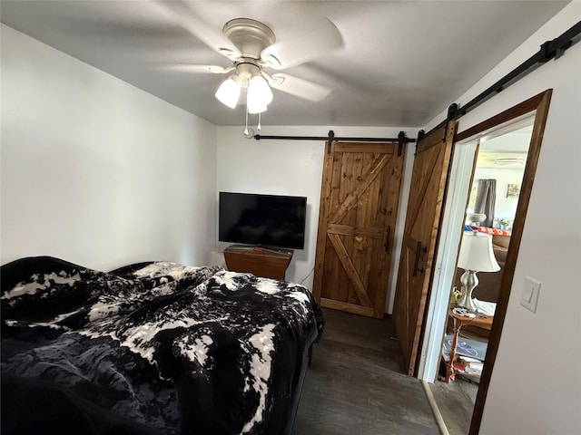 306 E Missoula Ave, Troy, MT 59935 - bedroom with a barn door, dark wood-style flooring, and ceiling fan