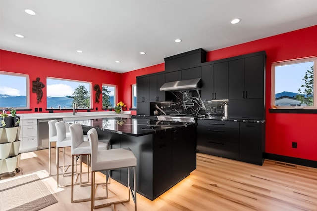 2813 Pine Lakes Ct, Stevensville, MT 59870 - kitchen featuring dark cabinets, wall chimney exhaust hood, recessed lighting, dishwasher, and light wood finished floors