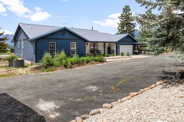 2813 Pine Lakes Ct, Stevensville, MT 59870 - ranch-style house featuring asphalt driveway, an attached garage, a metal roof, and a porch