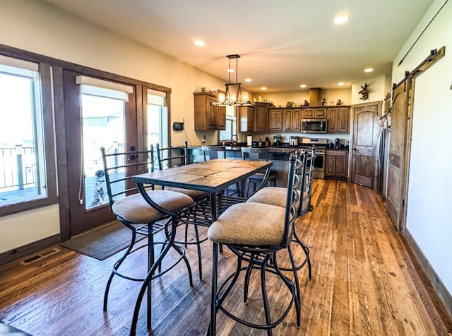 3012 Arendelle Rd, East Helena, MT 59635 - dining space featuring dark wood finished floors, a barn door, a chandelier, and recessed lighting