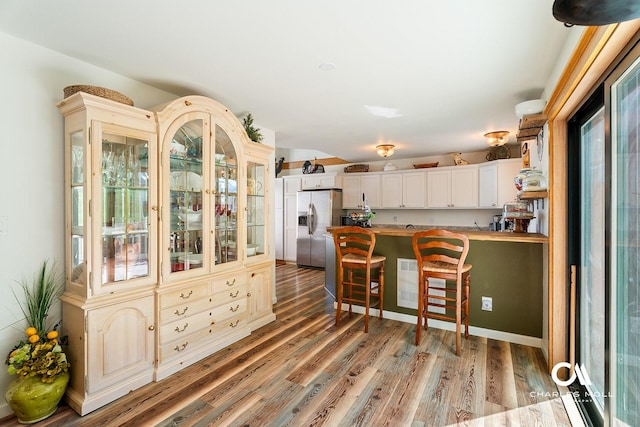2623 Gold Rush Ave, Helena, MT 59601 - kitchen featuring stainless steel refrigerator with ice dispenser, light wood finished floors, a peninsula, glass insert cabinets, and a kitchen bar