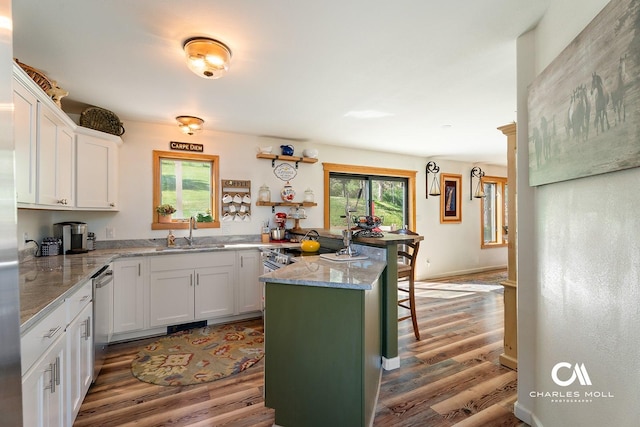 2623 Gold Rush Ave, Helena, MT 59601 - kitchen featuring wood finished floors, white cabinetry, light stone countertops, a breakfast bar area, and a peninsula