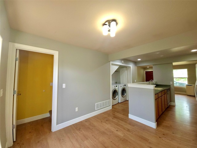 1109 Wyoming St, Belgrade, MT 59714 - kitchen featuring washer and dryer, light wood-style floors, brown cabinets, recessed lighting, and an island with sink