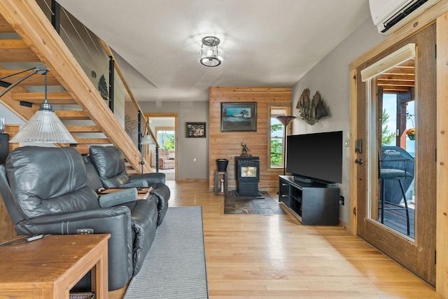 298 Lone Wolf Trl, Lakeside, MT 59922 - living room with a wall mounted air conditioner, wood finished floors, a wood stove, stairway, and wooden walls