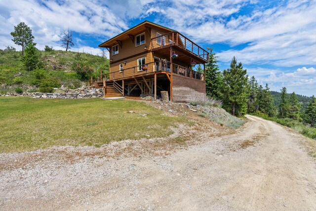298 Lone Wolf Trl, Lakeside, MT 59922 - rear view of house featuring a wooden deck, a lawn, driveway, and stairs