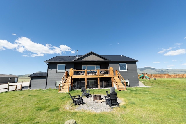 51 Whitehorse Rd, Townsend, MT 59644 - rear view of house with stairway, a fire pit, a deck with mountain view, a fenced backyard, and a playground