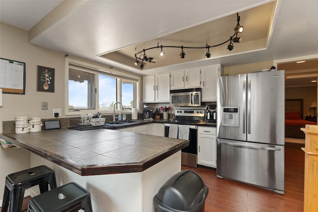918 36th Ave NE, Great Falls, MT 59404 - kitchen featuring stainless steel appliances, a peninsula, a breakfast bar, white cabinets, and dark wood-style floors